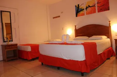 a bedroom with two beds with red and white sheets at Las Tilapias Hotel in San Ignacio