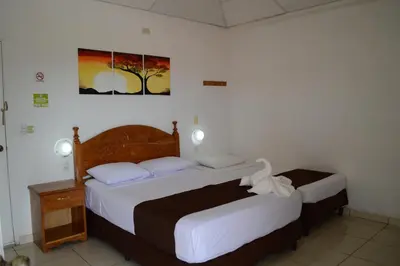 a bedroom with two beds and a picture on the wall at Las Tilapias Hotel in San Ignacio