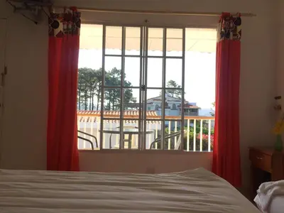 a bedroom with a bed and a window with red curtains at Las Tilapias Hotel in San Ignacio