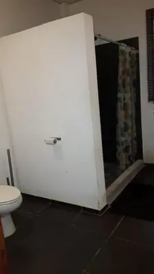 a bathroom with a white wall and a toilet at Hostal El Balsamo in El Sunzal