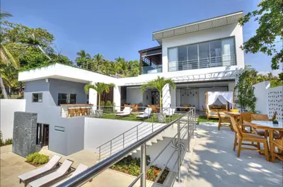 a white house with a patio with a table and chairs at Garten Hotel in El Zonte