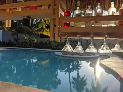 a swimming pool with wine glasses and a bar at Garten Hotel in El Zonte