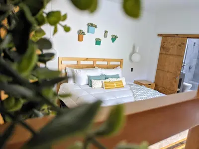 a bedroom with a bed with pillows and a plant at Garten Hotel in El Zonte