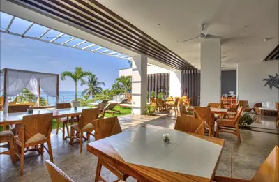 an outdoor patio with tables and chairs and the ocean at Garten Hotel in El Zonte