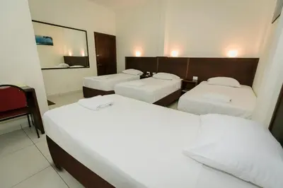 a hotel room with three beds and a mirror at Hotel Mediterraneo Inn in Santa Rosa de Lima