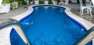 a swimming pool with blue water and white chairs at Hotel Mediterraneo Inn in Santa Rosa de Lima