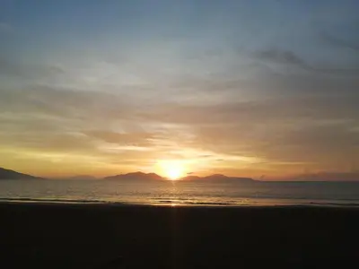 a sunset on the beach with mountains in the background at La Ceja Beach House in El Tamarindo
