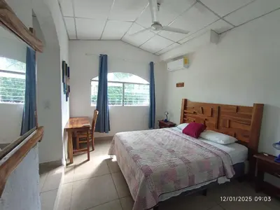 a bedroom with a bed and a desk and a window at La Ceja Beach House in El Tamarindo