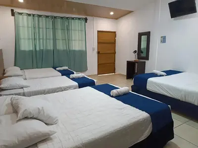 a room with four beds with blue and white sheets at El Patio de Don Moncho in Nueva San Salvador