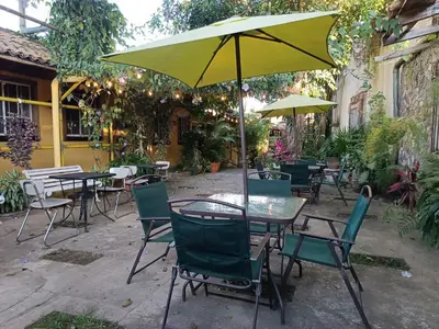 an outdoor patio with tables and chairs and an umbrella at El Patio de Don Moncho in Nueva San Salvador