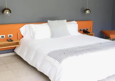 a bedroom with a large white bed with an orange headboard at Il Buongustaio in San Salvador