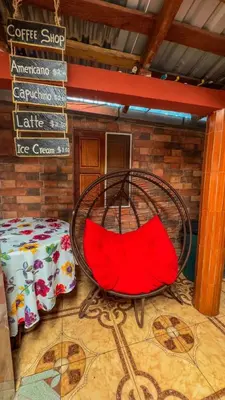 a red chair in a room with a table at Hostal Raíces de mi Pueblo in Suchitoto
