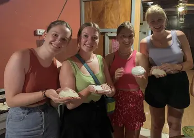 a group of four women standing together holding food at Hostal Raíces de mi Pueblo in Suchitoto