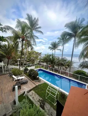 a swimming pool with palm trees and the ocean at Konchamar in La Libertad