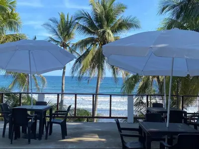 a patio with tables and umbrellas and the ocean at Konchamar in La Libertad