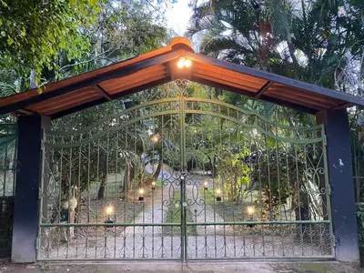 a gate to a garden with lights on it at Nanda Parbat Hostal in San Rafael Cedros