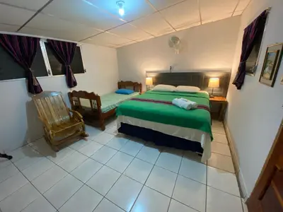 a bedroom with a bed and a chair in it at Nanda Parbat Hostal in San Rafael Cedros