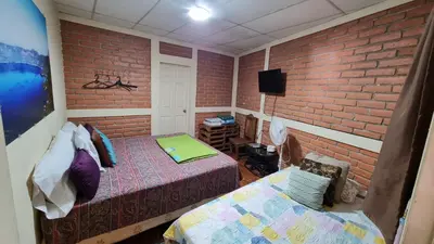 a bedroom with two beds and a brick wall at Hostal Las Veraneras Ataco in Concepción de Ataco