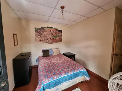 a bedroom with a bed and a painting on the wall at Hostal Las Veraneras Ataco in Concepción de Ataco