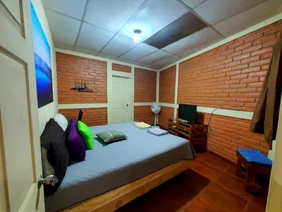 a bedroom with a bed and a brick wall at Hostal Las Veraneras Ataco in Concepción de Ataco