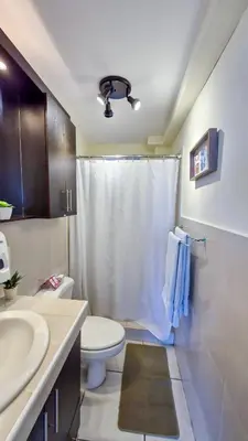 a bathroom with a toilet and a white shower curtain at Luxury Modrn Apartment, w/amazing view, 3BR,Escalon,Exclus,Secur in San Salvador