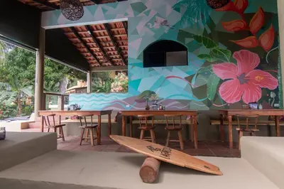 a restaurant with wooden tables and a surfboard on the floor at Lagarza Hostel in La Libertad