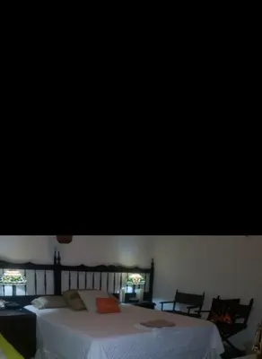 a bedroom with a large white bed and two chairs at Mendoza’s Guest House in Santa Ana