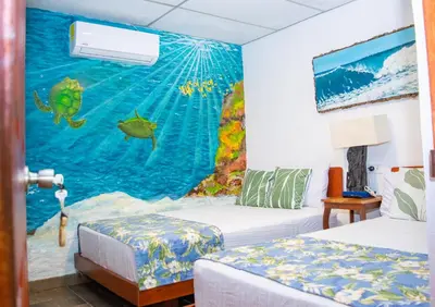 a room with two beds and a painting on the wall at Olas Permanentes El Zonte in El Zonte