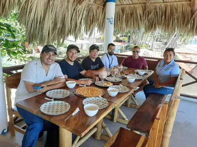 a group of people sitting around a wooden table at Olas Permanentes El Zonte in El Zonte