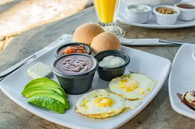 a plate with eggs and other food on a table at Olas Permanentes El Zonte in El Zonte