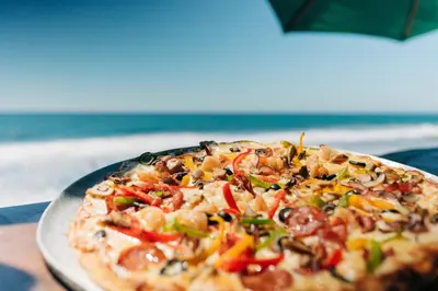 a pizza sitting on top of a plate on a table at Olas Permanentes El Zonte in El Zonte