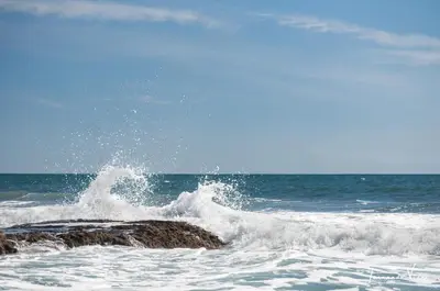 a wave crashing on a rock in the ocean at Olas Permanentes El Zonte in El Zonte