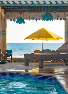 a table with an umbrella next to a swimming pool at Olas Permanentes El Zonte in El Zonte