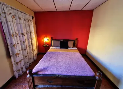a bedroom with a bed with a red wall at Hostal Juarez Ataco in Concepción de Ataco