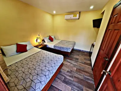 a hotel room with two beds and a television at Hostal Juarez Ataco in Concepción de Ataco