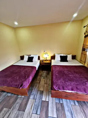 two beds in a room with wooden floors at Hostal Juarez Ataco in Concepción de Ataco