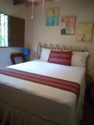 a bedroom with a large white bed with colorful pillows at Thermal Paradise Villa in Caluco