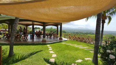a pavilion with tables and chairs and palm trees at Hotel Miraflores in El Cuco