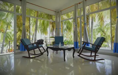 a living room with two chairs and a table and a room with windows at RocaSol Casa d´Mar in El Zonte