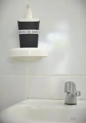 a bathroom sink with a cup and a faucet at RocaSol Casa d´Mar in El Zonte