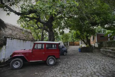 a red jeep parked next to a tree at RocaSol Casa d´Mar in El Zonte