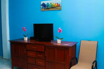 a wooden dresser with a television and two chairs at Sabas Beach Resort in La Libertad