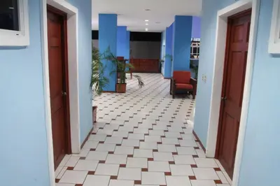 an empty hallway with blue walls and a white tile floor at Sabas Beach Resort in La Libertad