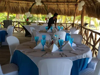 a table with white chairs and blue glasses on it at Sabas Beach Resort in La Libertad