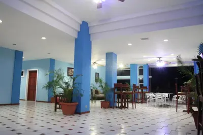 a lobby with blue columns and tables and chairs at Sabas Beach Resort in La Libertad