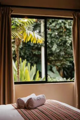 two towels sitting on a bed in front of a window at Casa 1800 Ataco Hotel Boutique in Concepción de Ataco
