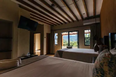 a bedroom with two beds and a large window at Casa 1800 Ataco Hotel Boutique in Concepción de Ataco