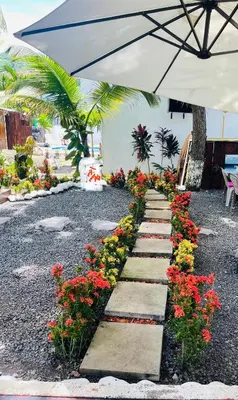 a pathway with flowers and an umbrella at The Beach Break Hotel El Zonte in El Zonte