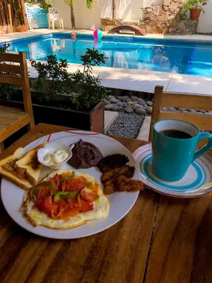 a table with a plate of food and a cup of coffee at The Beach Break Hotel El Zonte in El Zonte