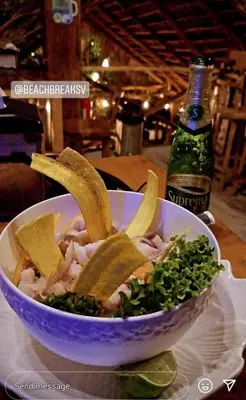 a salad in a bowl on a table with a bottle at The Beach Break Hotel El Zonte in El Zonte